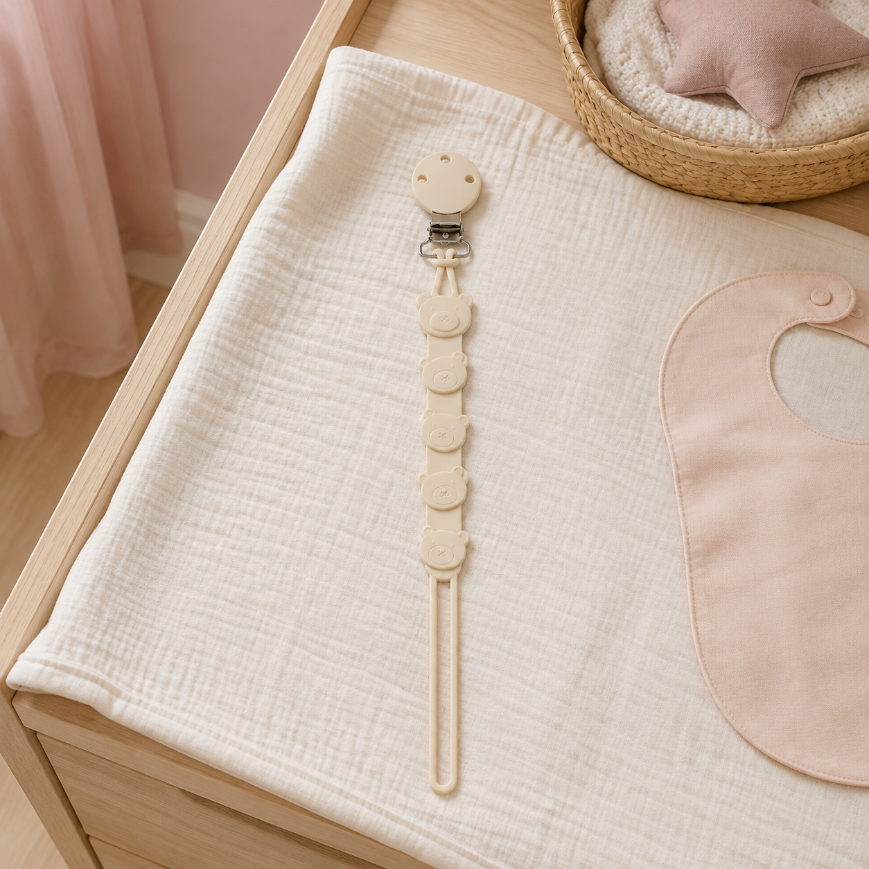 Attache-tétine ours beige en silicone sur une table à langer