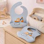 Bavoir bébé en silicone motif pelleteuse près d’un sac à langer