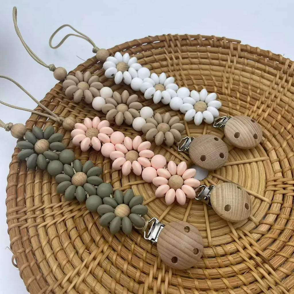 Attache Tétine Petite Fleur Marguerite en silicone, un accessoire pratique et stylé pour garder la tétine à portée.