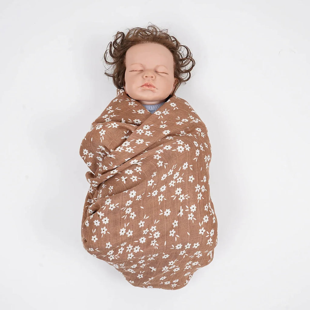 Lange bébé fleuri en mousseline présenté autour d’un nourrisson sous surveillance