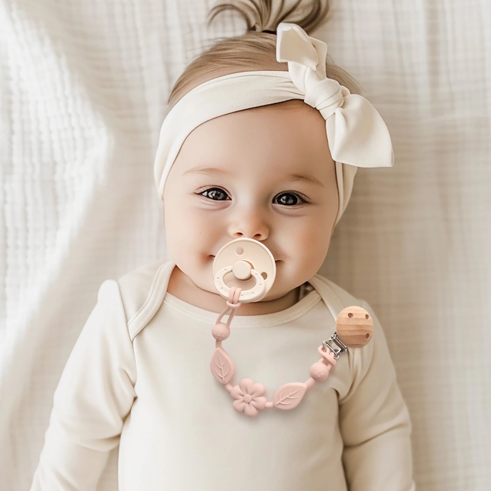 Attache-tétine fleur rose portée par un bébé