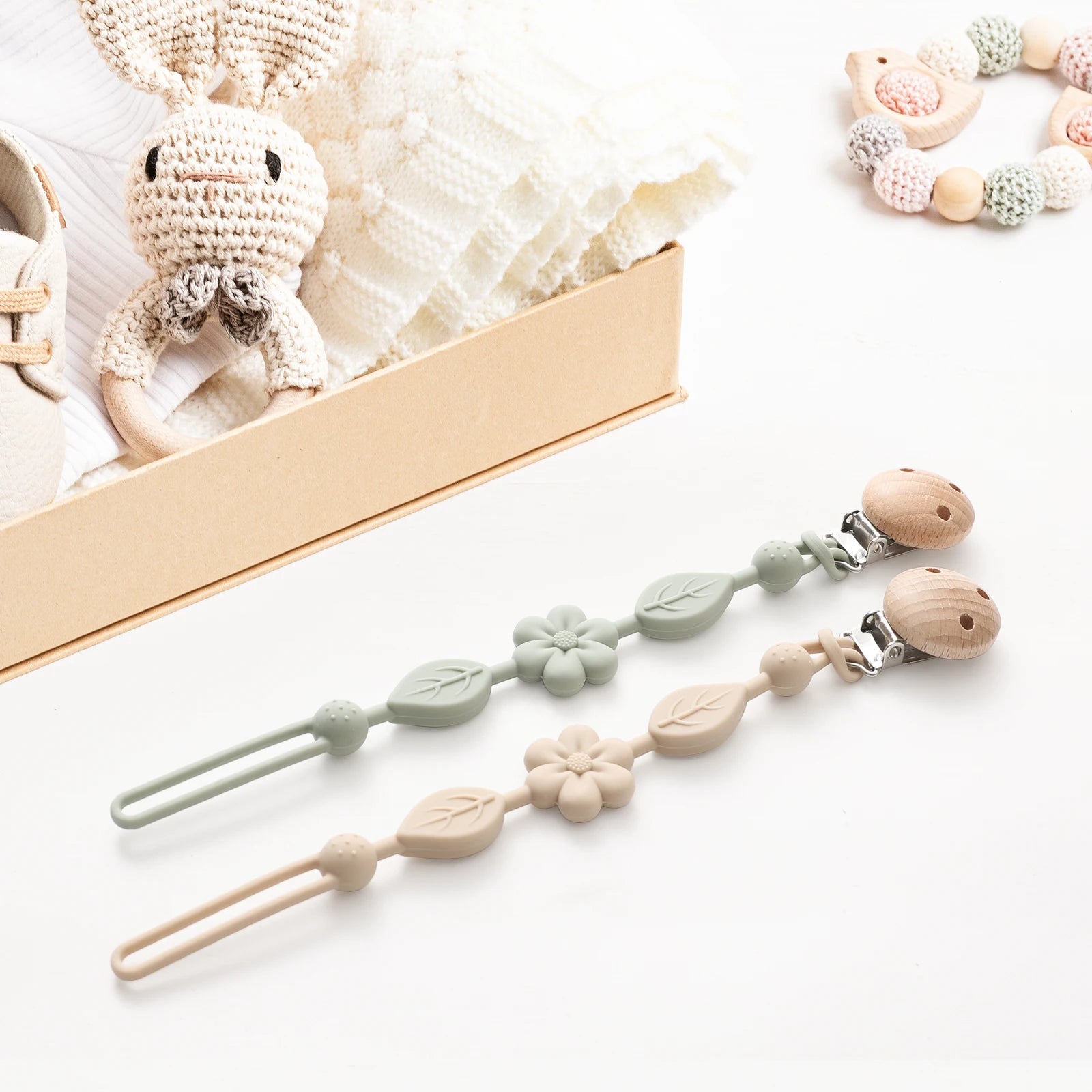Attaches-tétine fleur sauge et beige présentées avec un coffret naissance