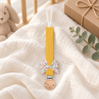 Attache-tétine en tissu jaune moutarde avec nœud fleuri et pince en bois